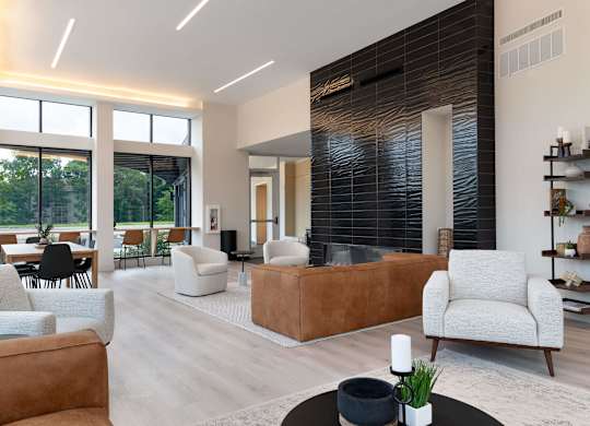 A modern living room with a brown leather couch and a white armchair.