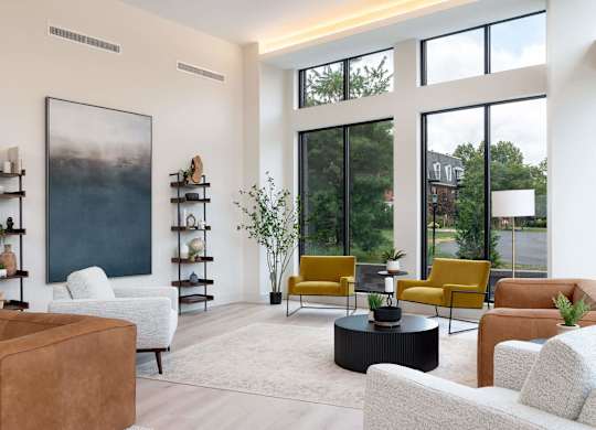 A living room with a large window, a painting, and a variety of seating options.