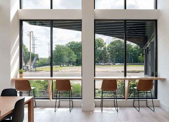 A room with a table and chairs in front of a large window with a view of the outside.