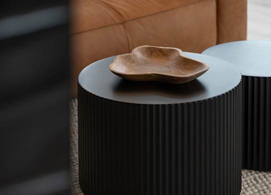 A wooden bowl sits on a black table.
