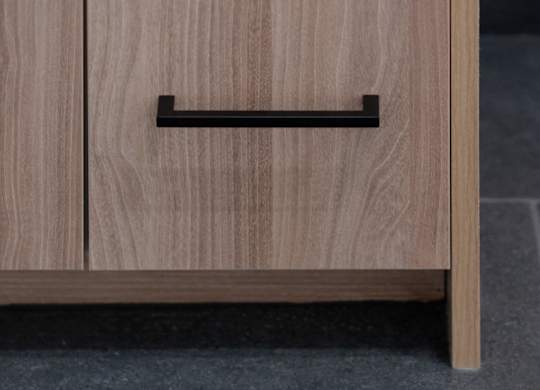 A wooden drawer with a black handle is placed on a grey floor.