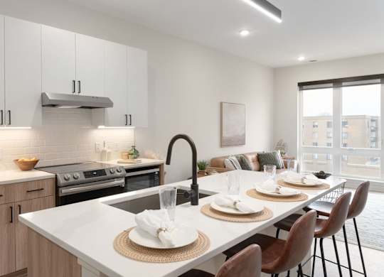 A modern kitchen with a dining table set for two.
