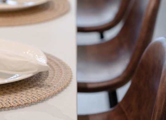 Brown chairs are placed in front of a table with plates.