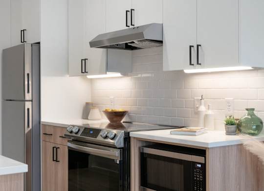 A modern kitchen with a stainless steel refrigerator, a microwave, and a range hood.