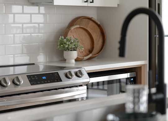 A modern kitchen with a stove top oven and a black faucet.
