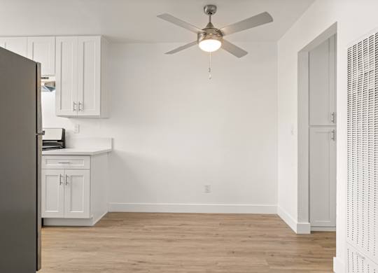 A room with a ceiling fan and a refrigerator.