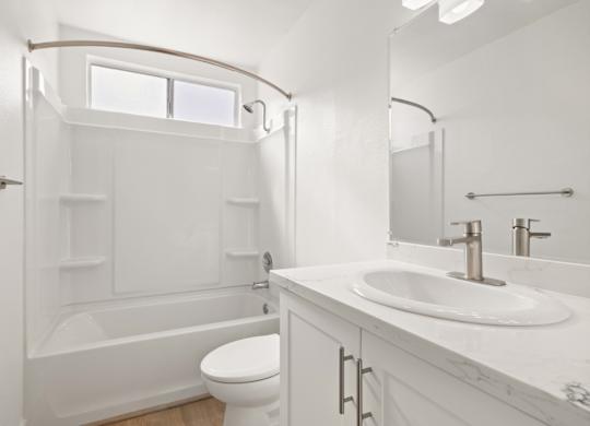 A white bathroom with a toilet, sink, and tub.