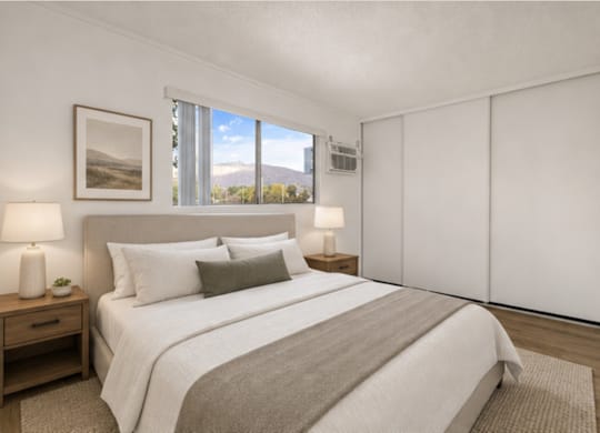 A bedroom with a large bed, two lamps, and a picture on the wall.