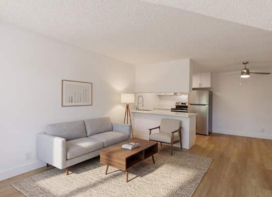 A living room with a grey couch, a wooden coffee table, and a white kitchen area in the background.