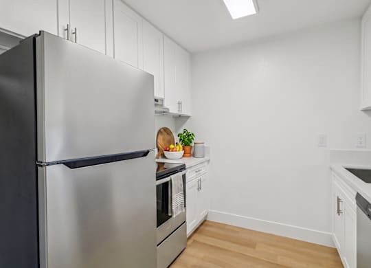 A kitchen with a black refrigerator and white cabinets.