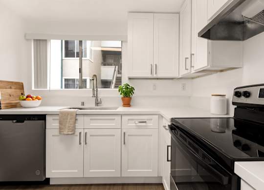 A modern kitchen with white cabinets and black appliances.