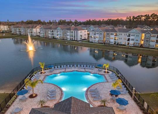 A beautiful sunset view of a pool and resort-style buildings.