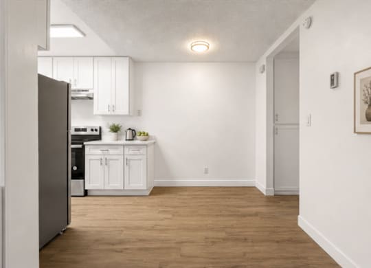 A kitchen with white cabinets and a refrigerator.
