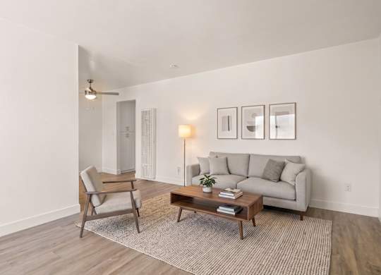 A living room with a grey couch, a chair, a coffee table, and pictures on the wall.