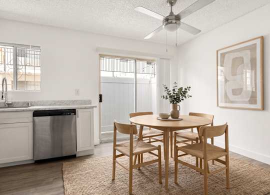 A dining room with a table set for two and a plant on the table.