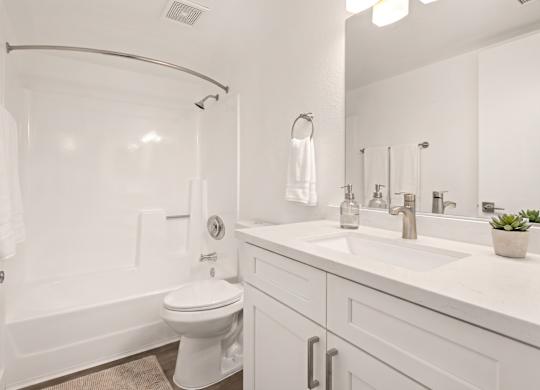 A white bathroom with a toilet, sink, and bathtub.