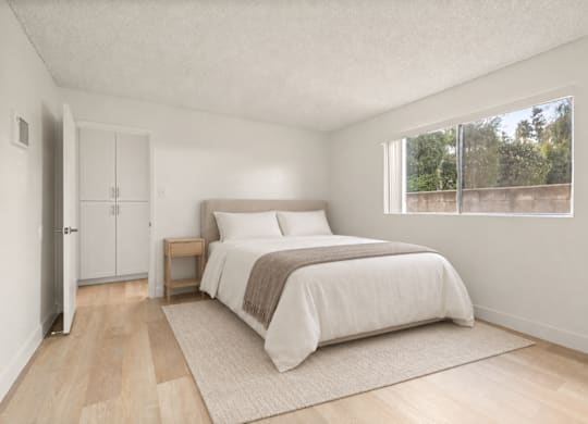 A bedroom with a bed, nightstand, and a window overlooking a fence.