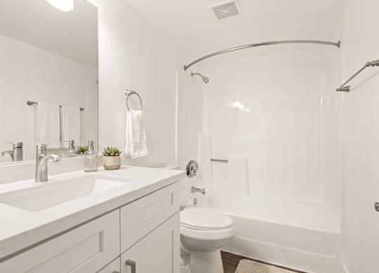 A white bathroom with a toilet, sink, and bathtub.