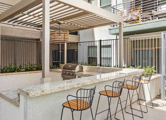 A patio with a bar and chairs under a wooden roof.