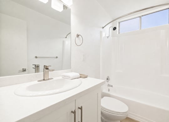 A white bathroom with a sink, toilet, and bathtub.