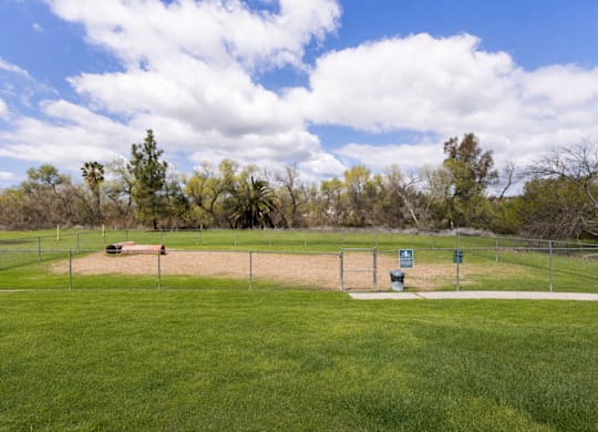 A baseball field with a fence and a sign in the distance.