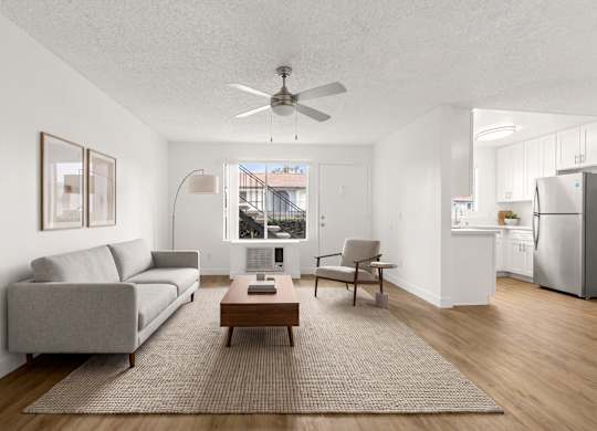 A living room with a grey couch, a brown coffee table, and a ceiling fan.