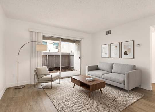 A living room with a grey couch, a chair, a table and pictures on the wall.