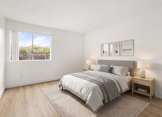 A bedroom with a large bed and a window overlooking a fence.