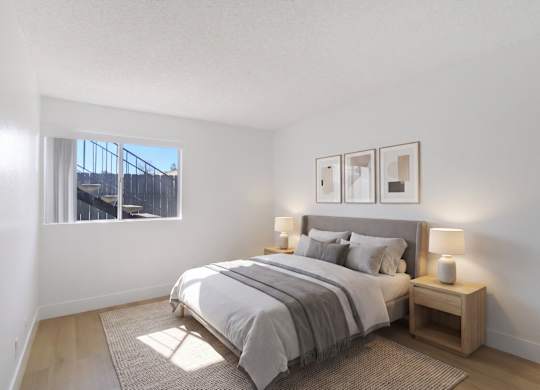 A bedroom with a large bed and a window overlooking a fence.