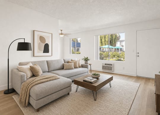 A living room with a grey couch, a coffee table, and a lamp.