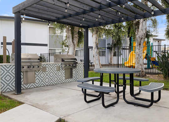 A picnic area with a grill and a table under a canopy.