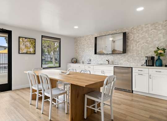 A kitchen with a table and chairs in front of a fridge and cabinets.
