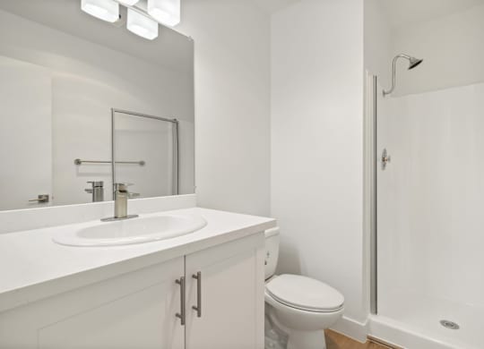A white bathroom with a toilet, sink, and shower.