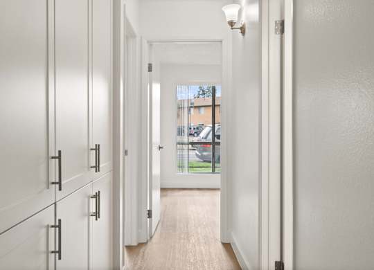 A long hallway with white doors and a light on the wall.