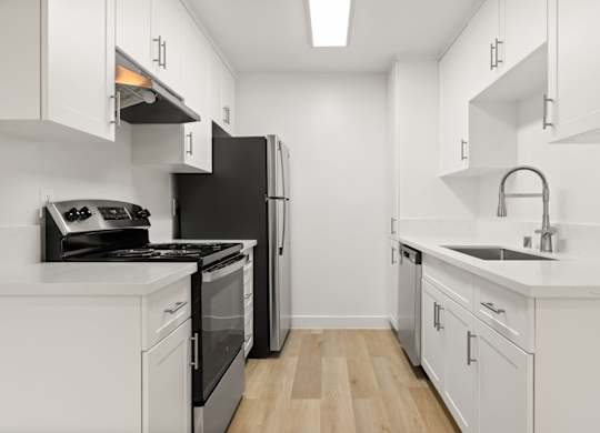 A kitchen with black appliances and white cabinets.