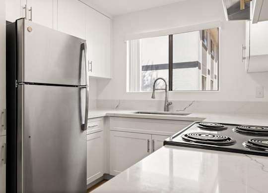 A modern kitchen with a stainless steel refrigerator and a white countertop.