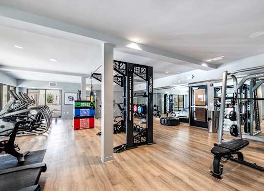 A gym with a variety of equipment including treadmills, weights, and exercise machines.