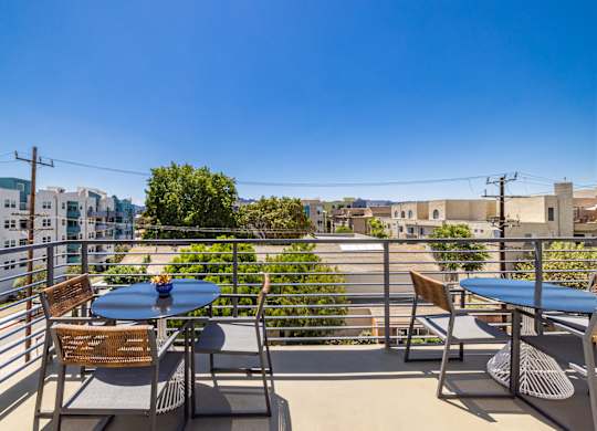 A balcony with a table and chairs overlooks a cityscape.