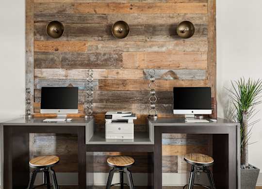 A wooden desk with two computers and a printer on it.