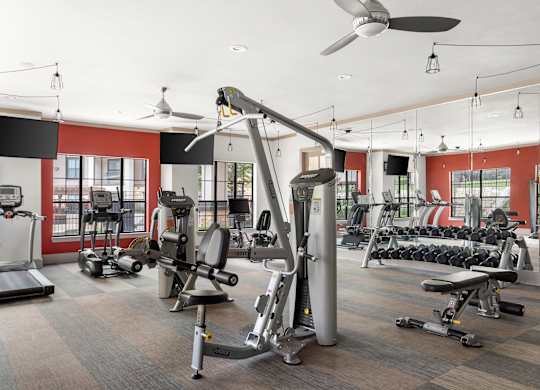 A gym with a variety of equipment including treadmills, weights, and exercise machines.