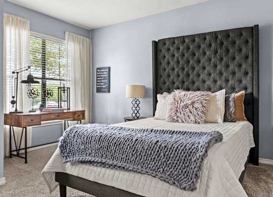 A bedroom with a bed, desk, and chair.