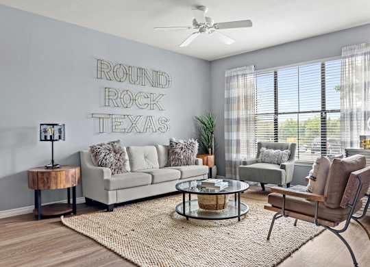 A living room with a couch, chair, and a rug in front of a wall with