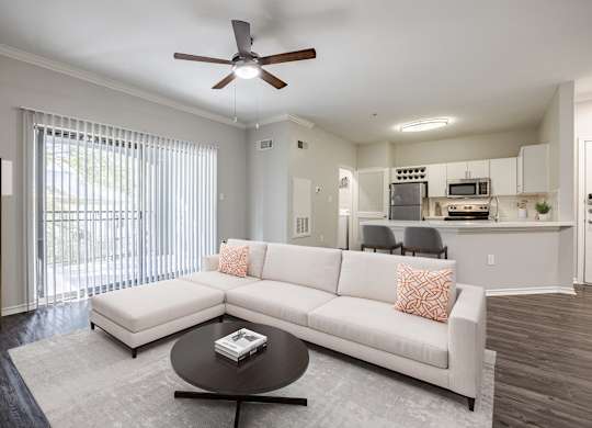 A modern living room with a white couch and a ceiling fan.