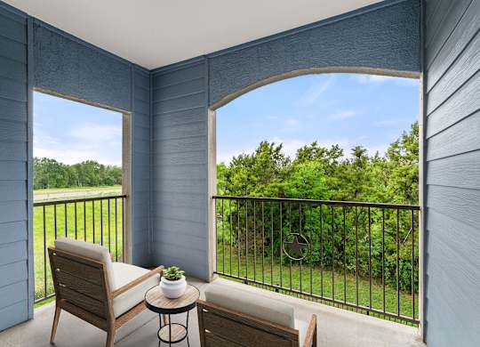 A balcony with a chair and a table with a plant on it.