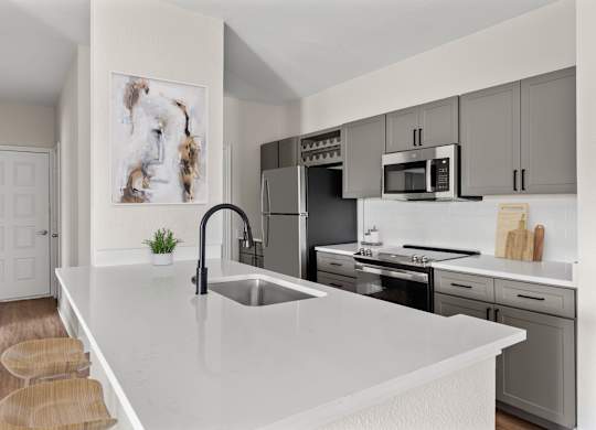 A modern kitchen with a white countertop and stainless steel appliances.