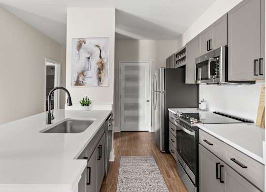 A modern kitchen with a refrigerator, oven, and microwave.