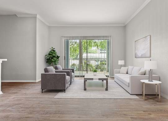A living room with a grey couch, a grey armchair, a white side table, and a white lamp.