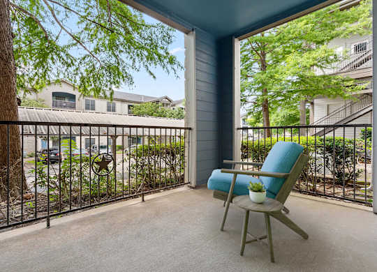 A chair sits on a patio with a view of a street and houses.