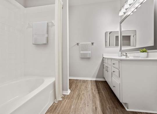 A white bathroom with a tub, sink, and mirror.