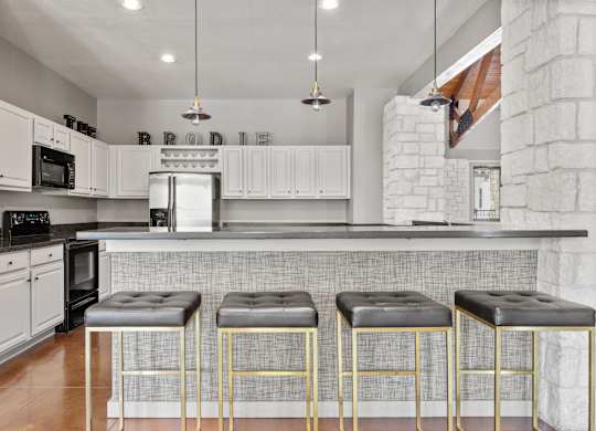 A kitchen with white cabinets and a black and gold bar stool.